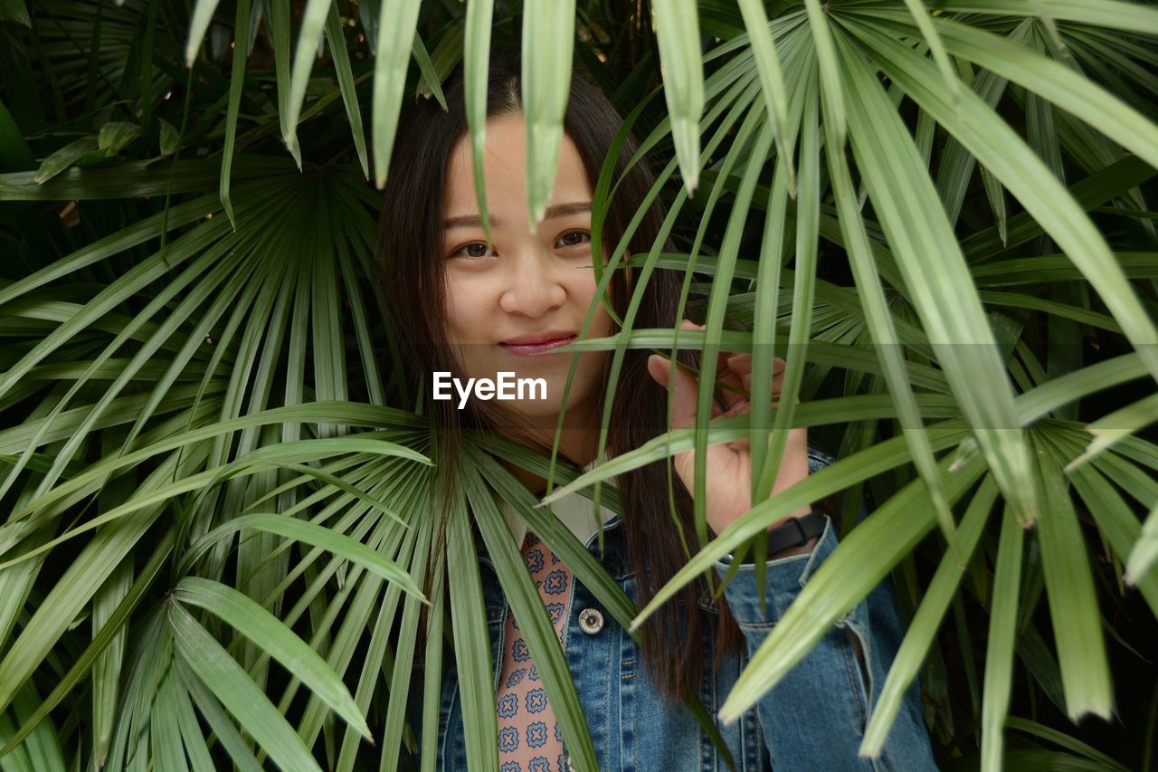 Portrait of young woman standing amidst plants