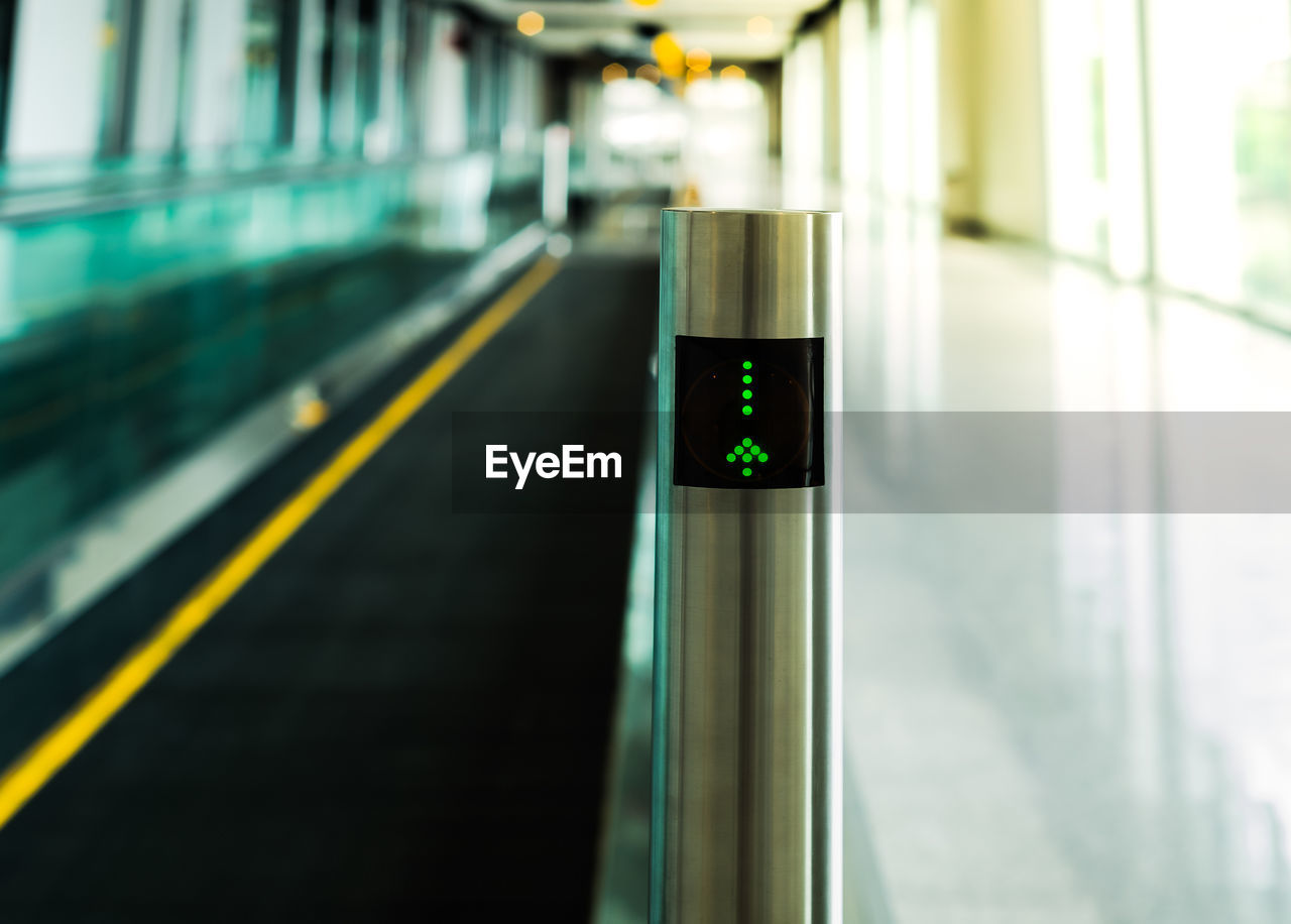 Close-up of arrow sign by moving walkway