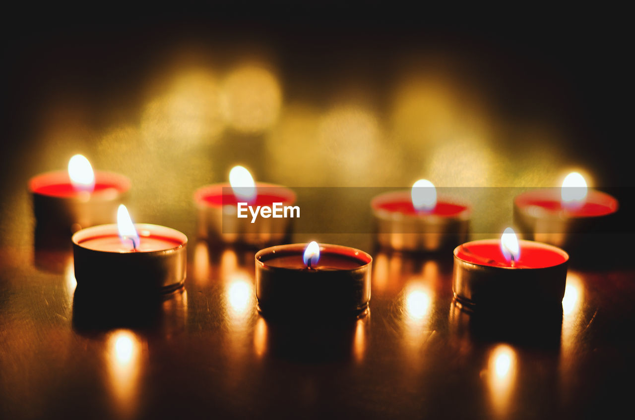 Burning candles with festive bokeh on black background. holiday concept, prayer and hope.