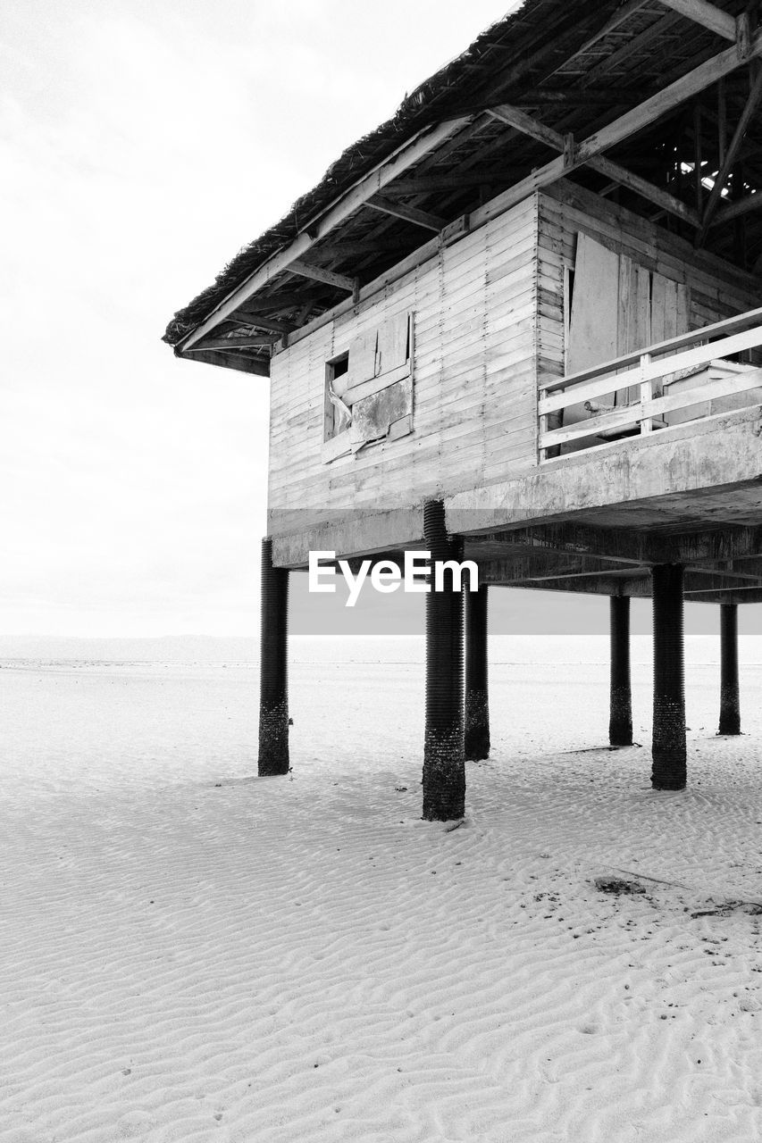 Built structure on beach by sea against sky