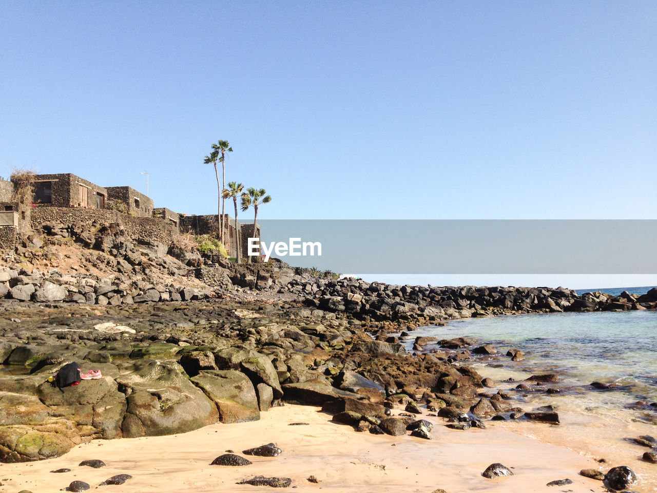 Scenic view of rocky shore against clear sky