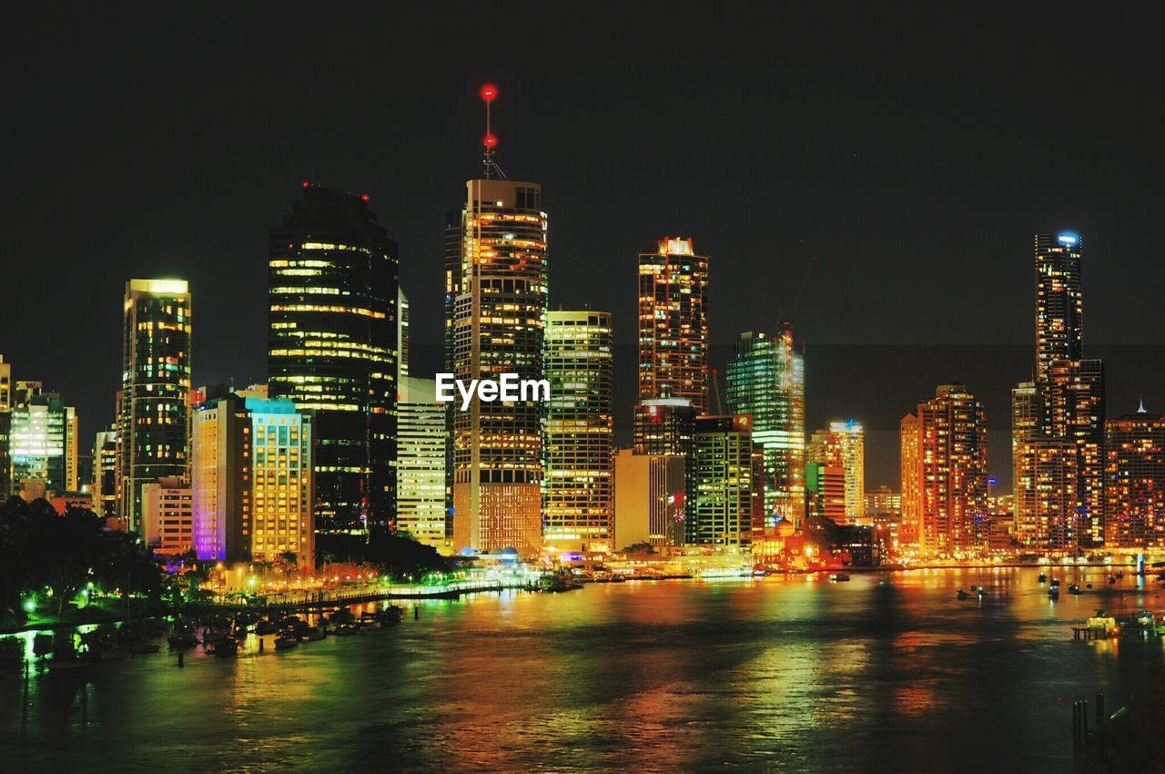 Illuminated buildings in front of river at night