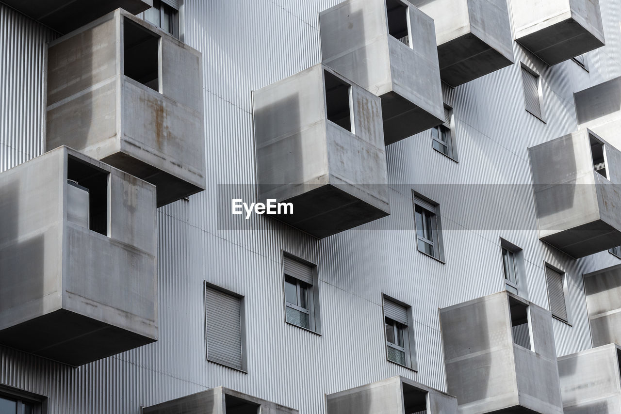 From below exterior of residential house with windows and various gray balconies located on street of city