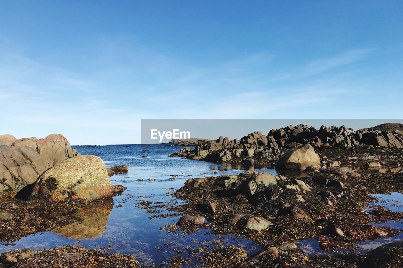 Scenic view of rocks in sea against blue sky