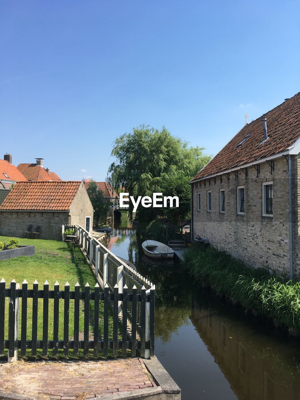 Canal by house against clear sky