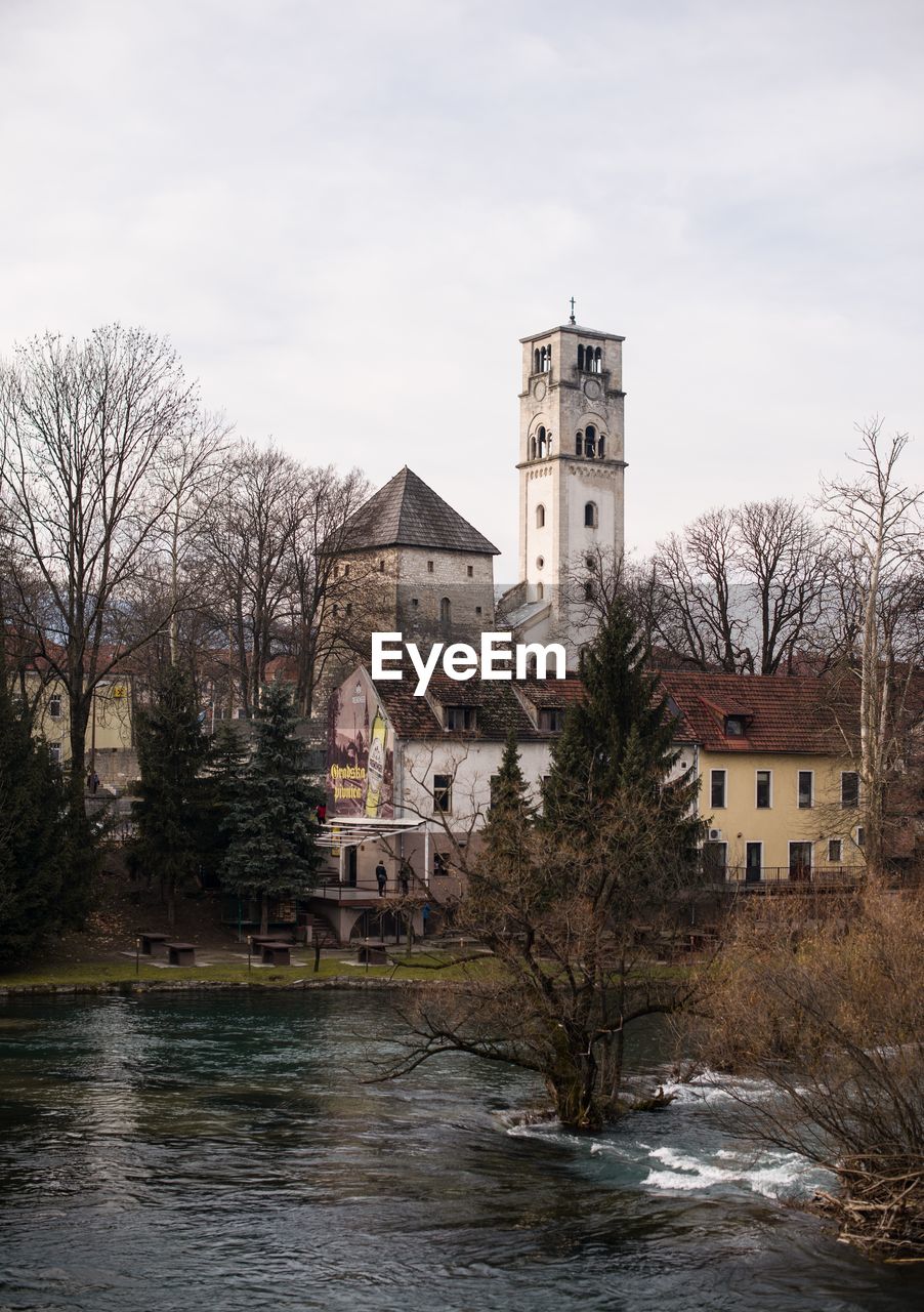 Buildings by river against sky