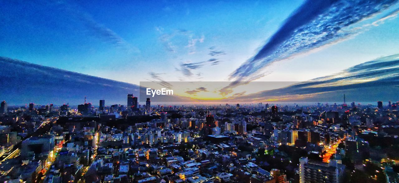 Aerial view of city buildings against sky during sunset
