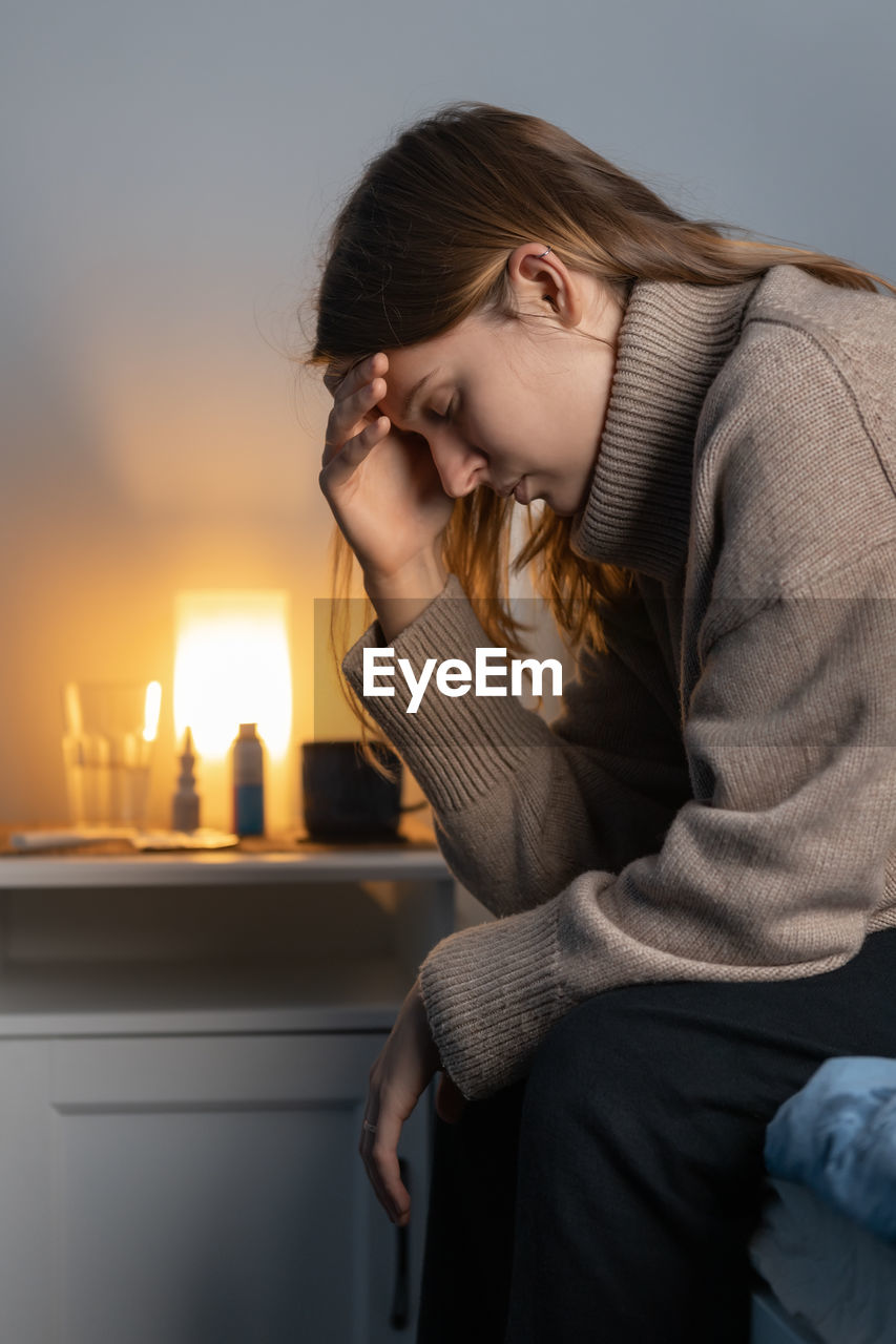 Depressed woman sitting on bed at home