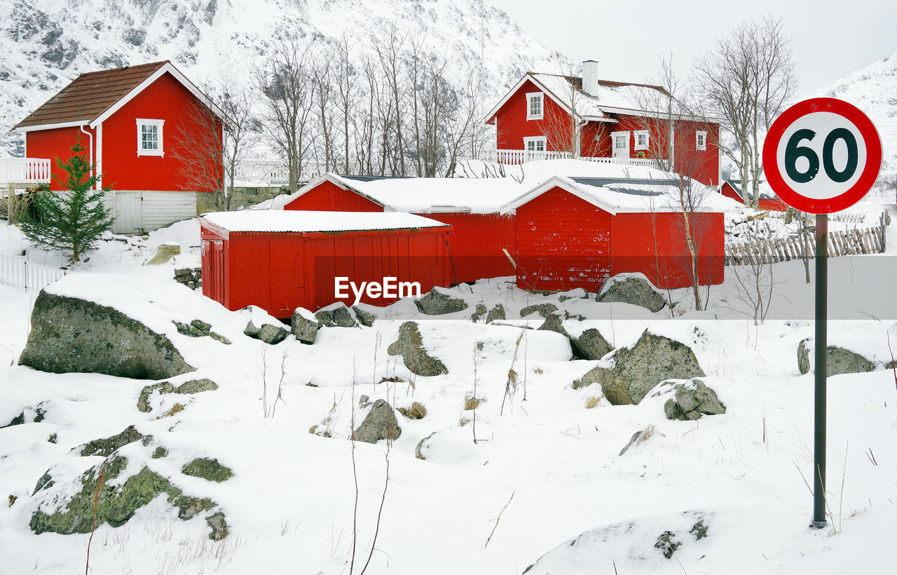 ROAD SIGN ON SNOW COVERED FIELD BY BUILDINGS