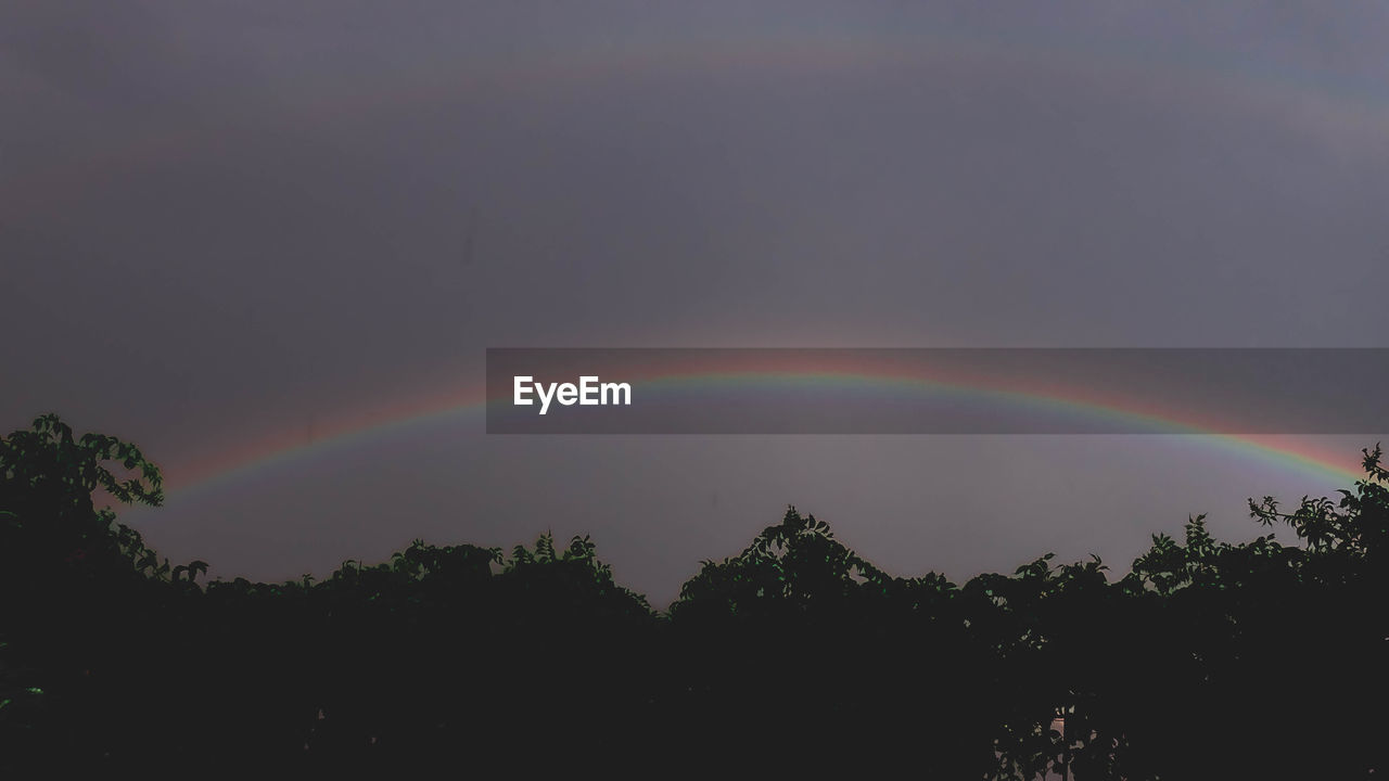 LOW ANGLE VIEW OF RAINBOW AGAINST SKY DURING SUNSET