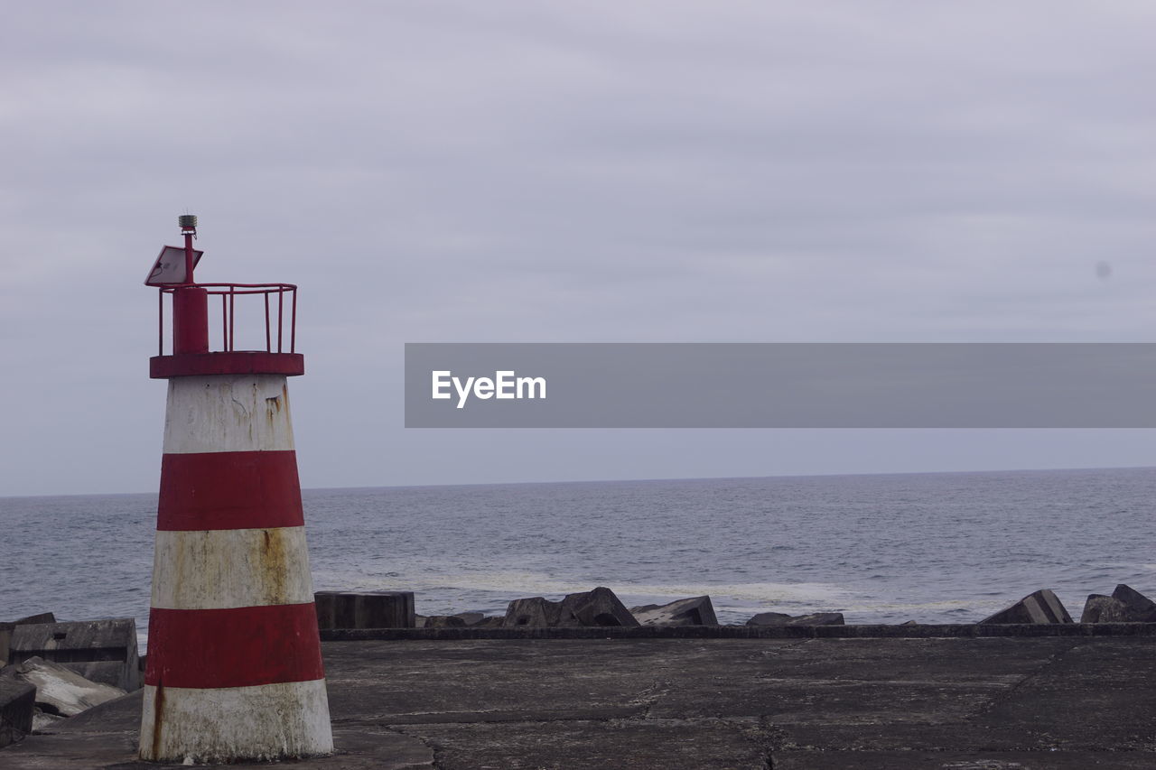 LIGHTHOUSE AMIDST SEA AGAINST SKY