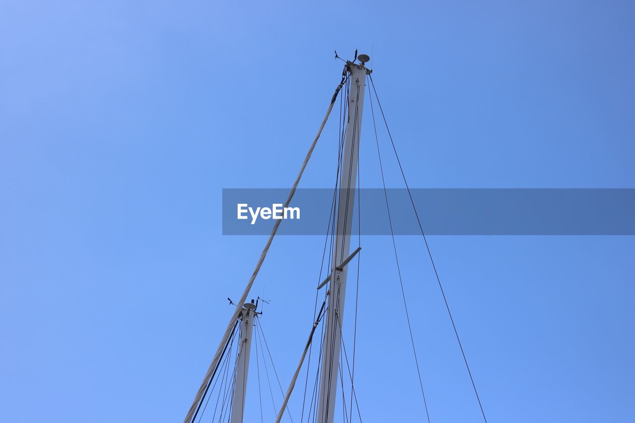 Low angle view of cranes against clear blue sky