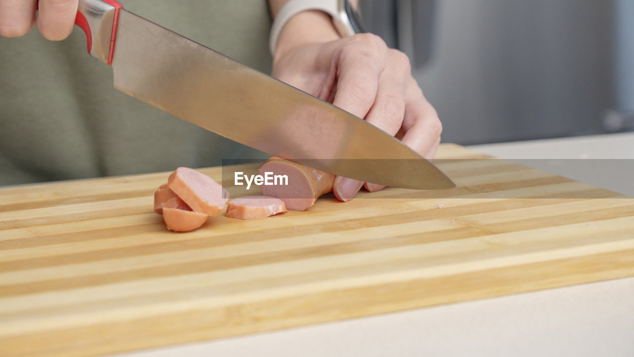 midsection of woman holding knife on wooden table