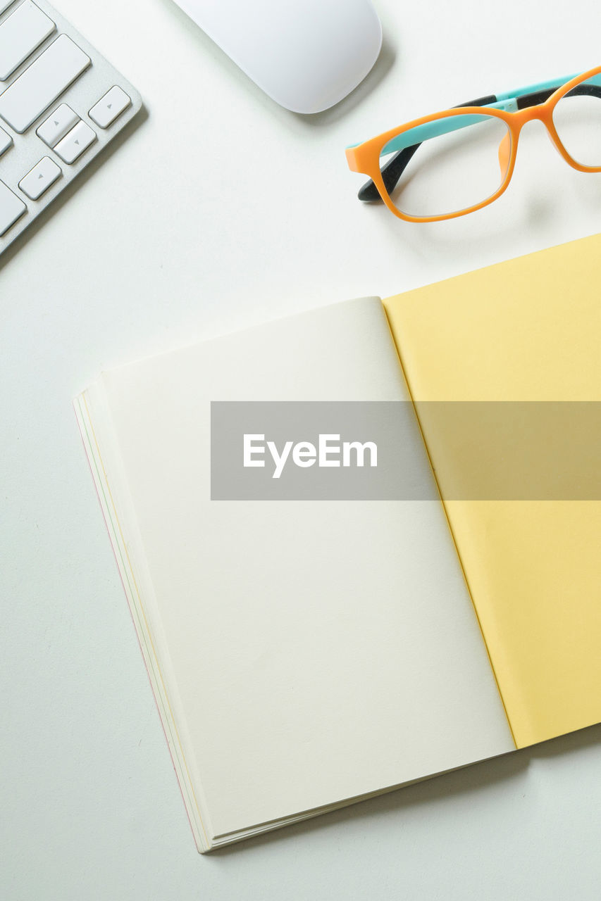 Directly above shot of blank book by eyeglasses on table