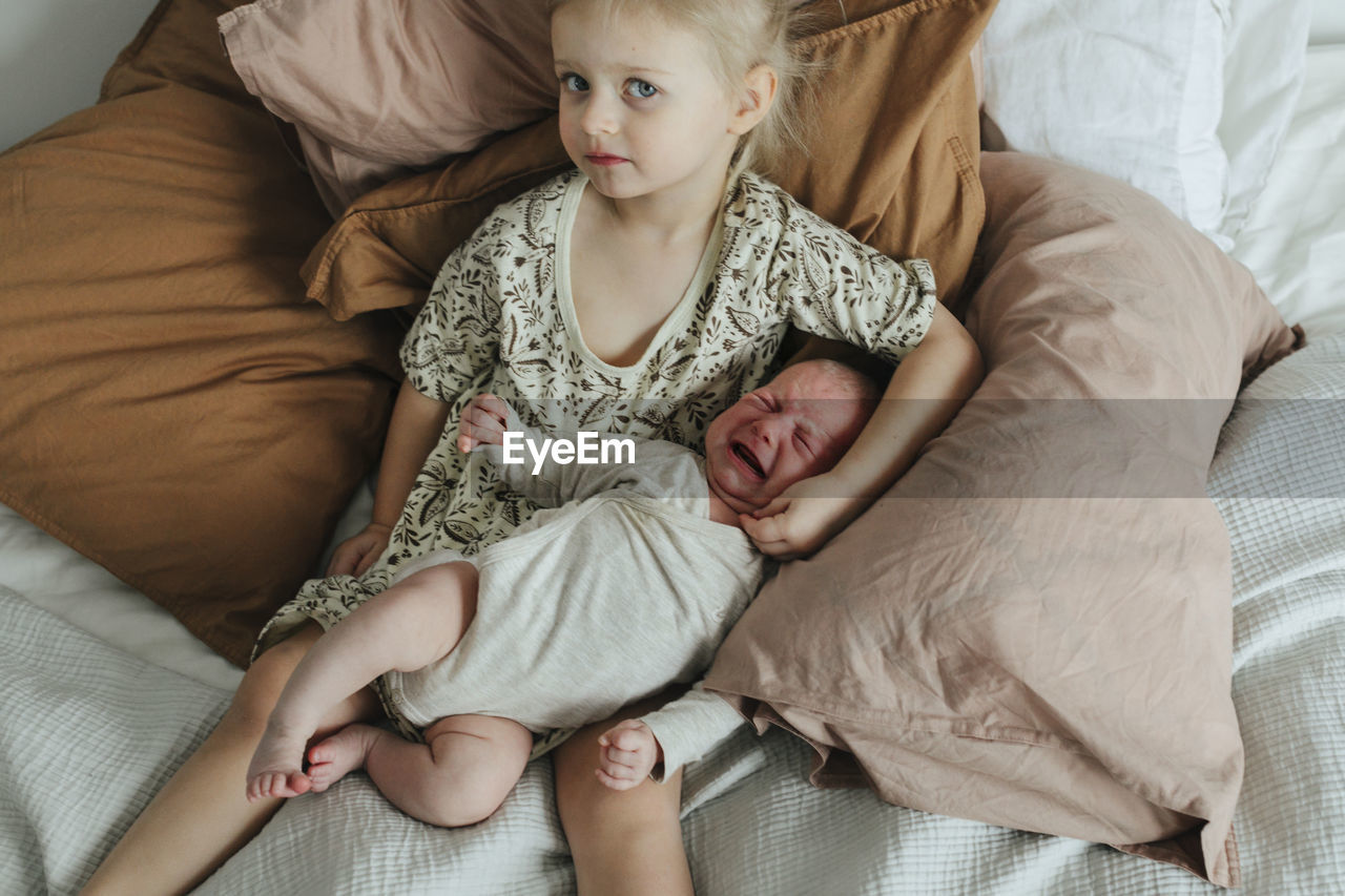 Girl with newborn sibling on bed