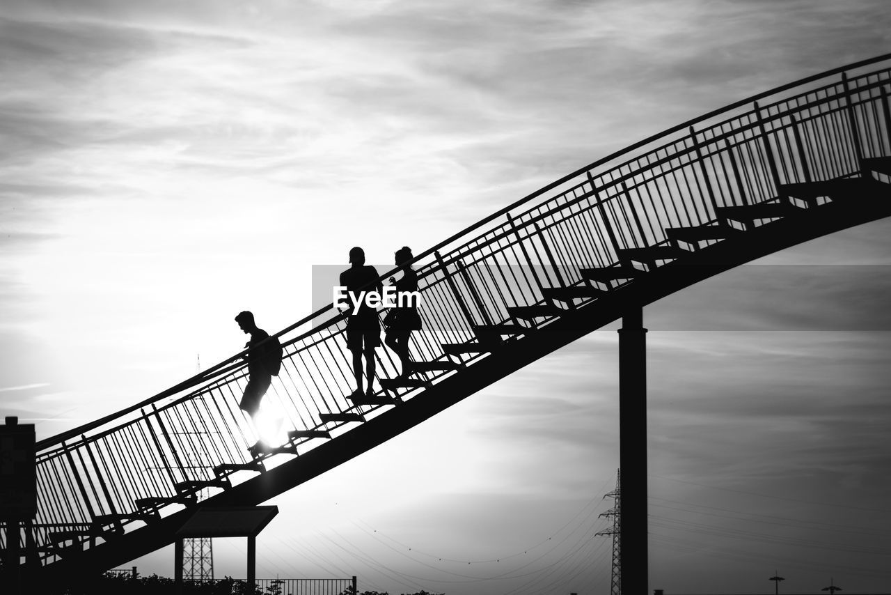 Low angle view of silhouette people walking on stairs against sky