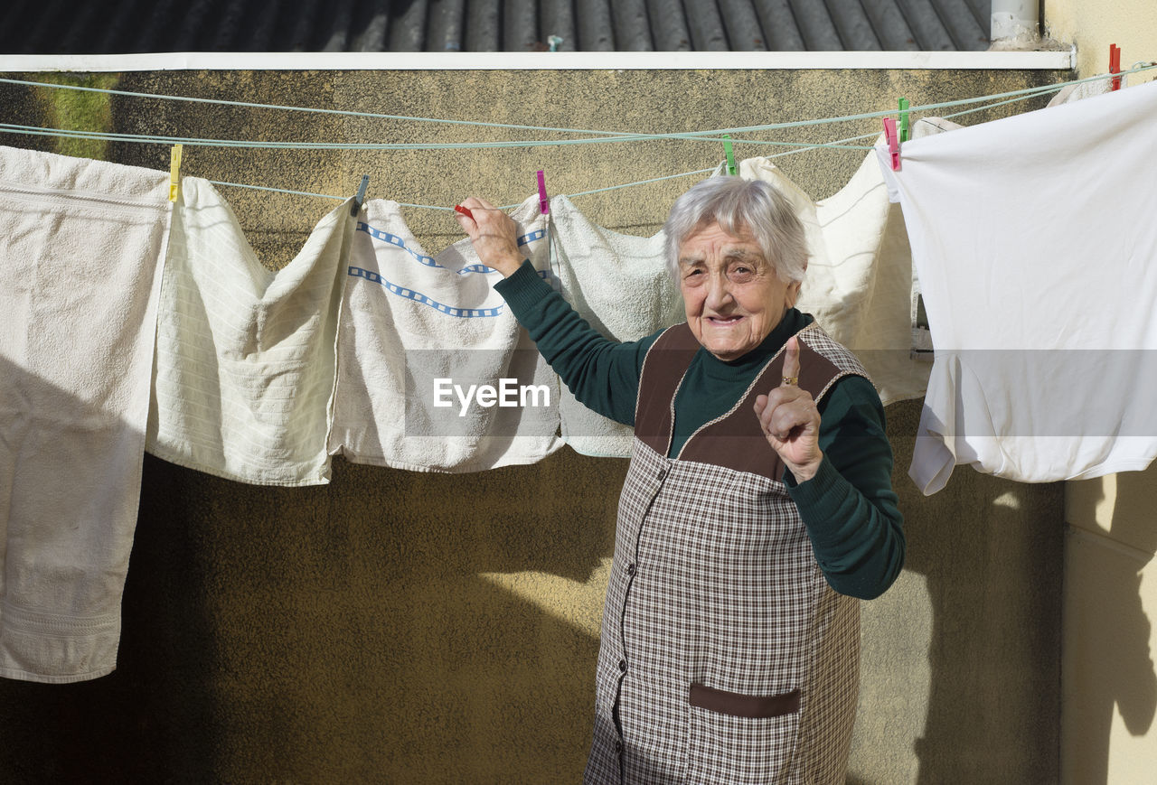 Portrait of senior woman drying clothes outdoors