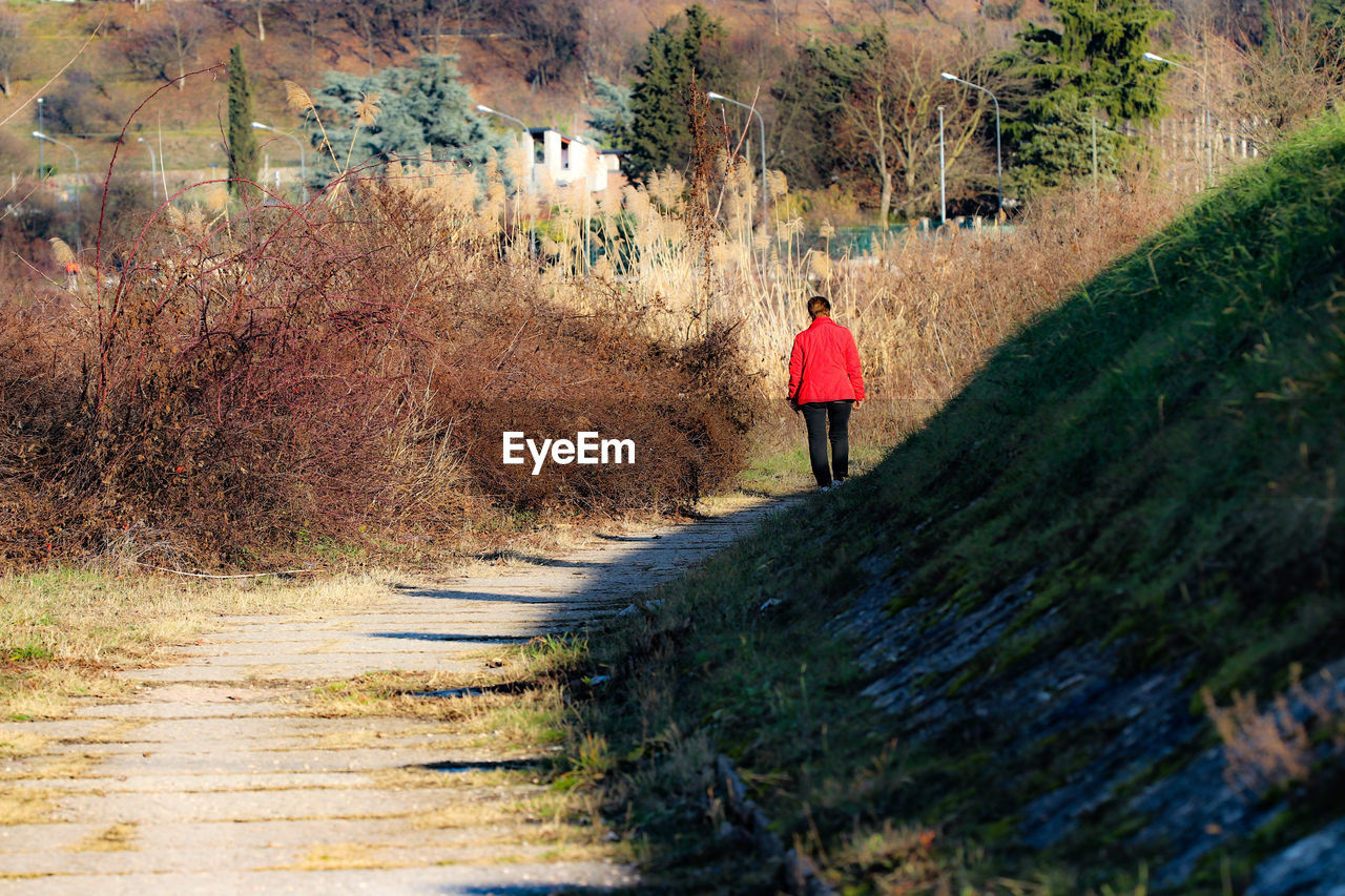 Rear view of woman walking on dirt road