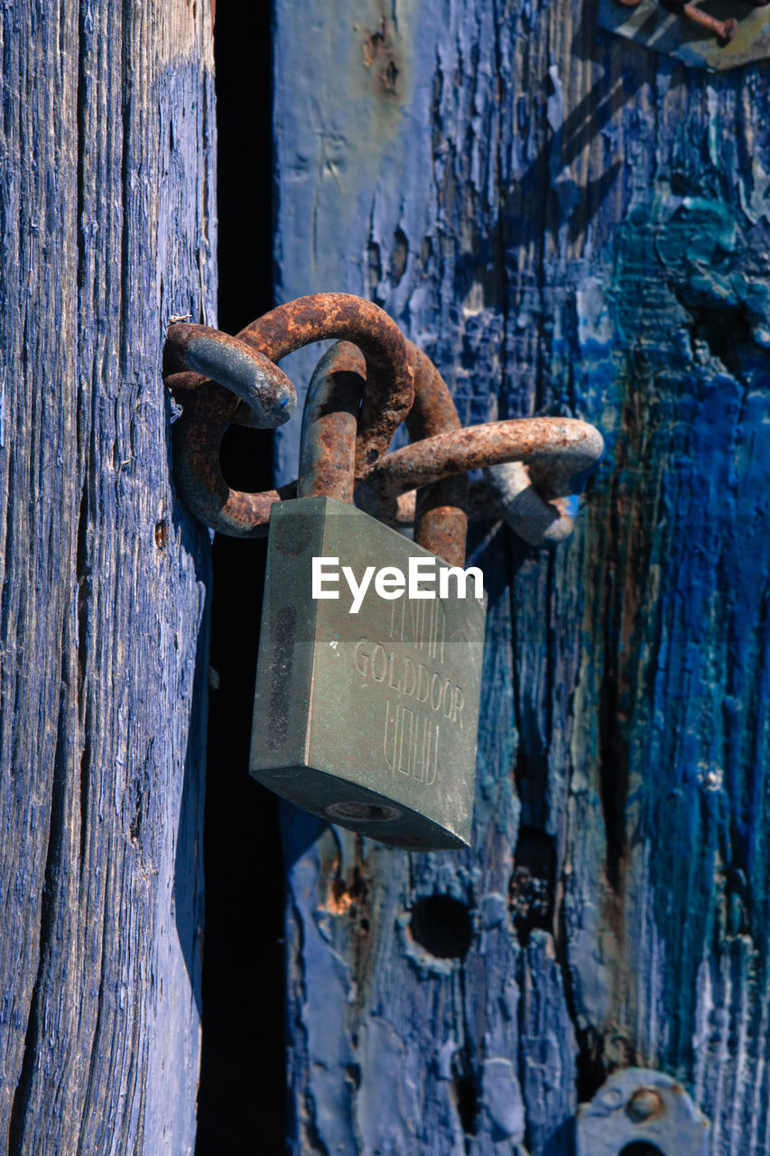 Close-up of rusty metal chain on wooden post