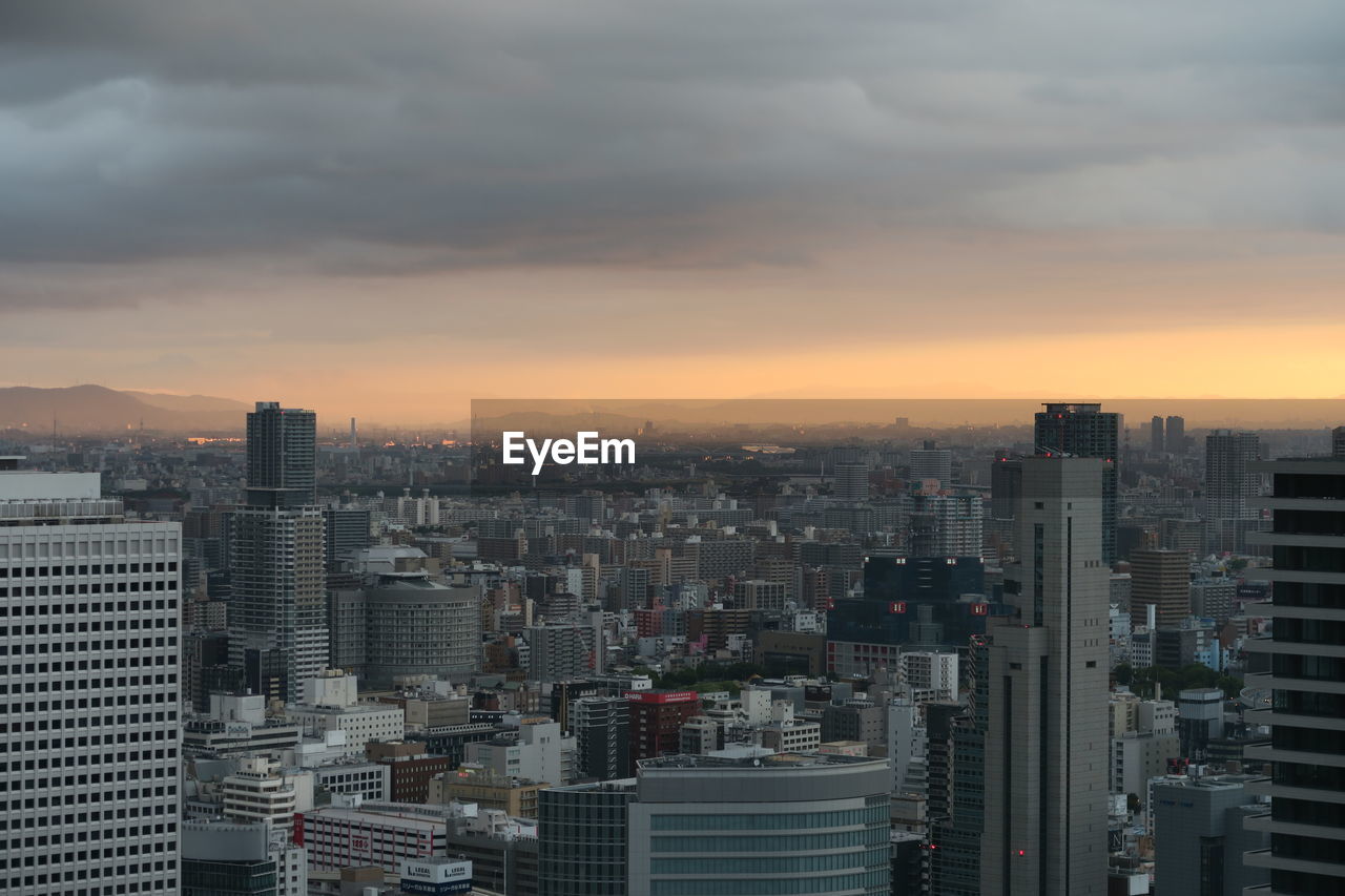 Aerial view of buildings in city against sky during sunset