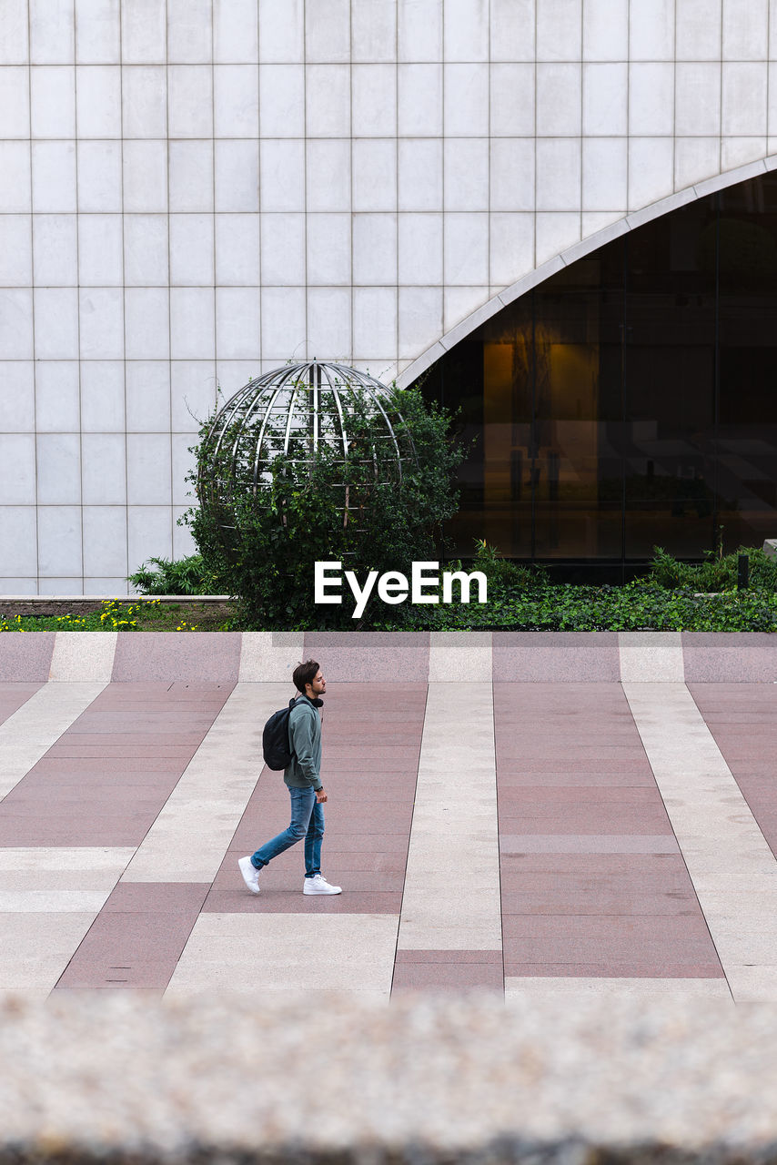 Lonely male student with backpack walking in university campus