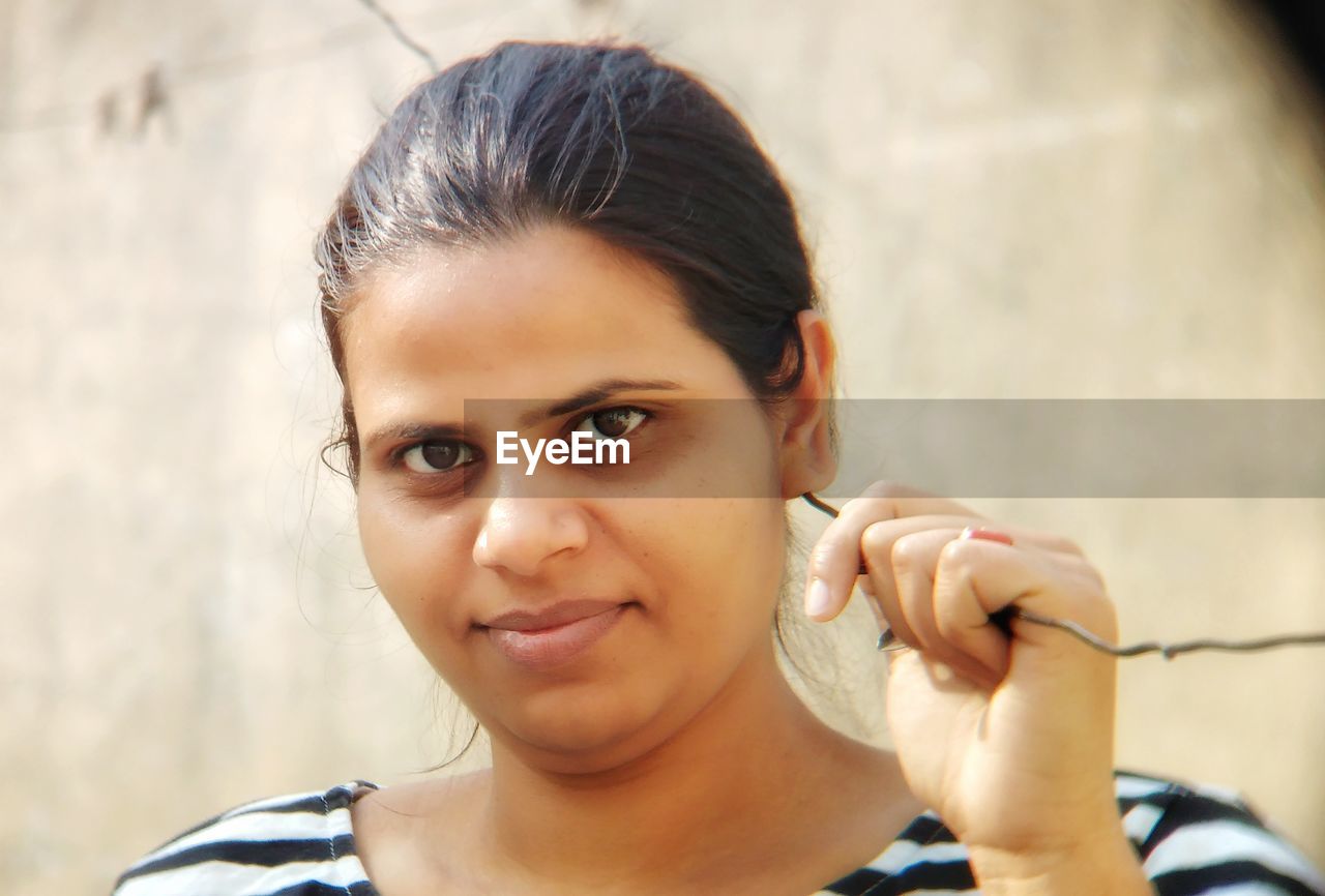 Close-up portrait of young woman standing against wall