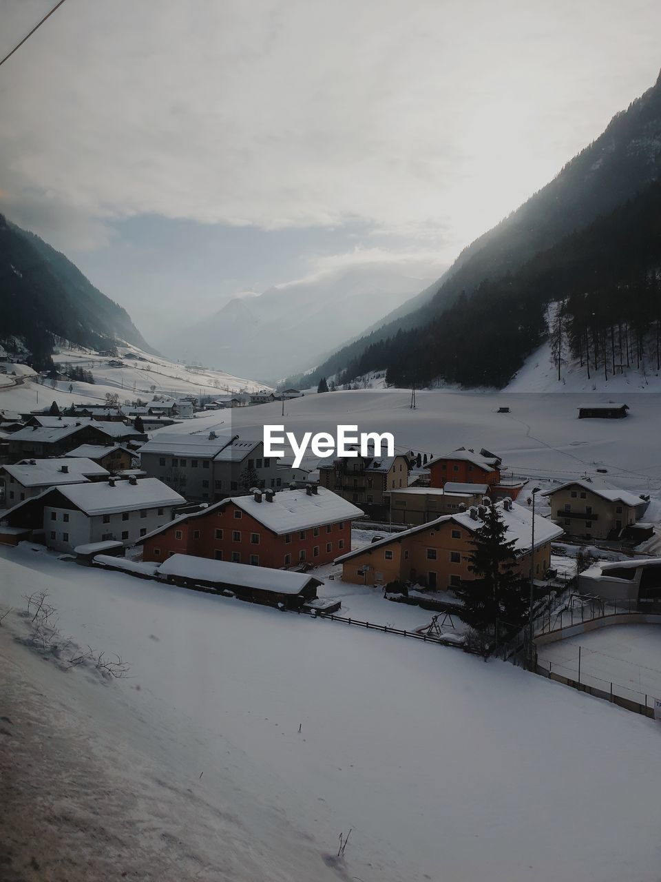 Houses by snow covered mountains against sky