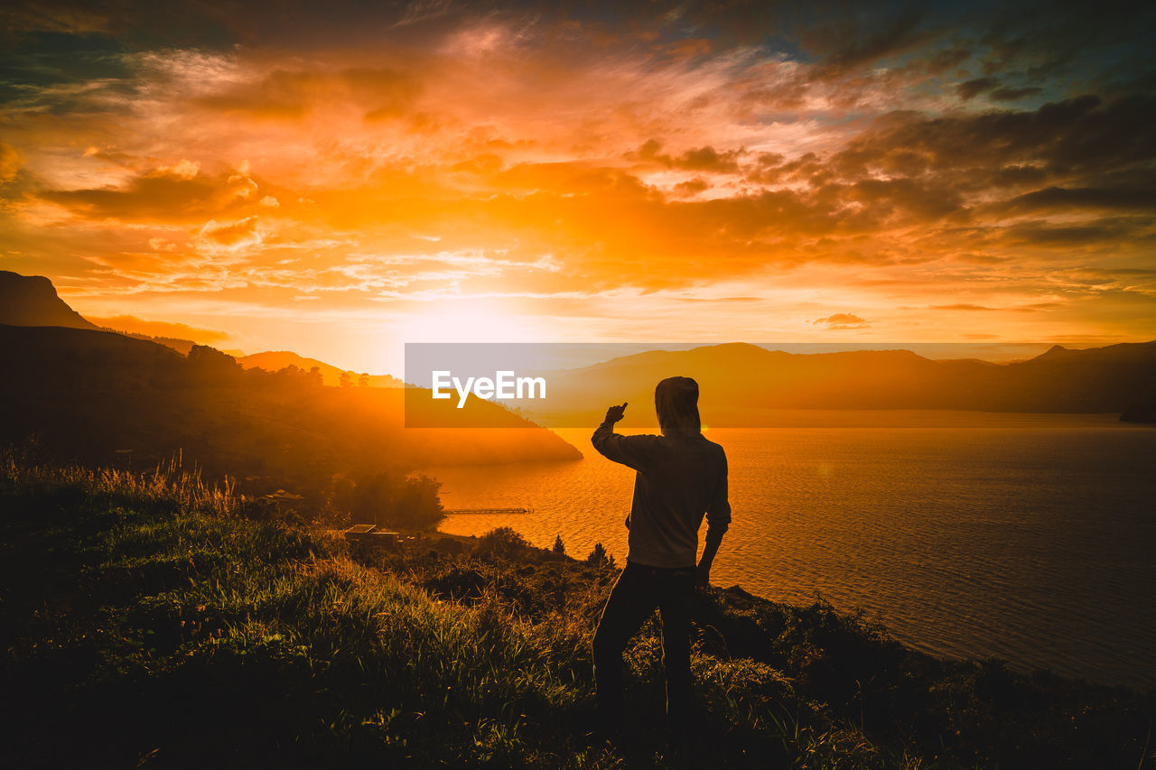 SILHOUETTE MAN STANDING ON MOUNTAIN DURING SUNSET