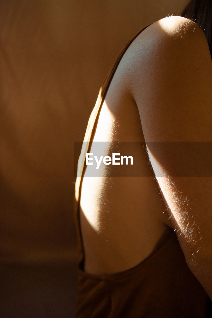 Sunlight falling on woman by wall