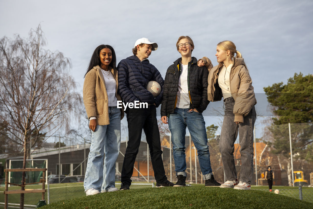 Portrait of teenage friends standing on grass