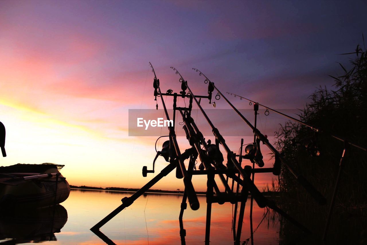 SILHOUETTE CRANES AGAINST SKY AT SUNSET