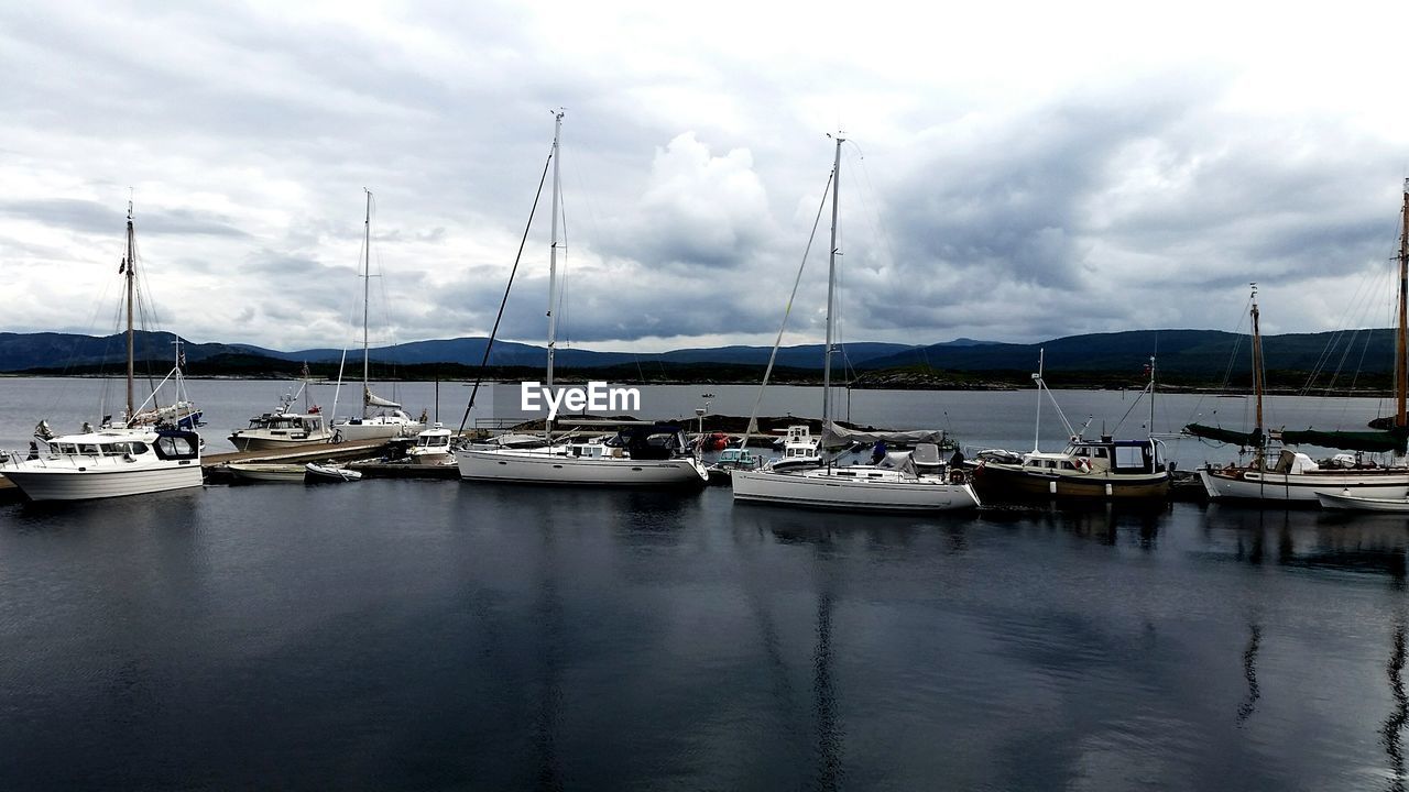 Boats moored at harbor against sky