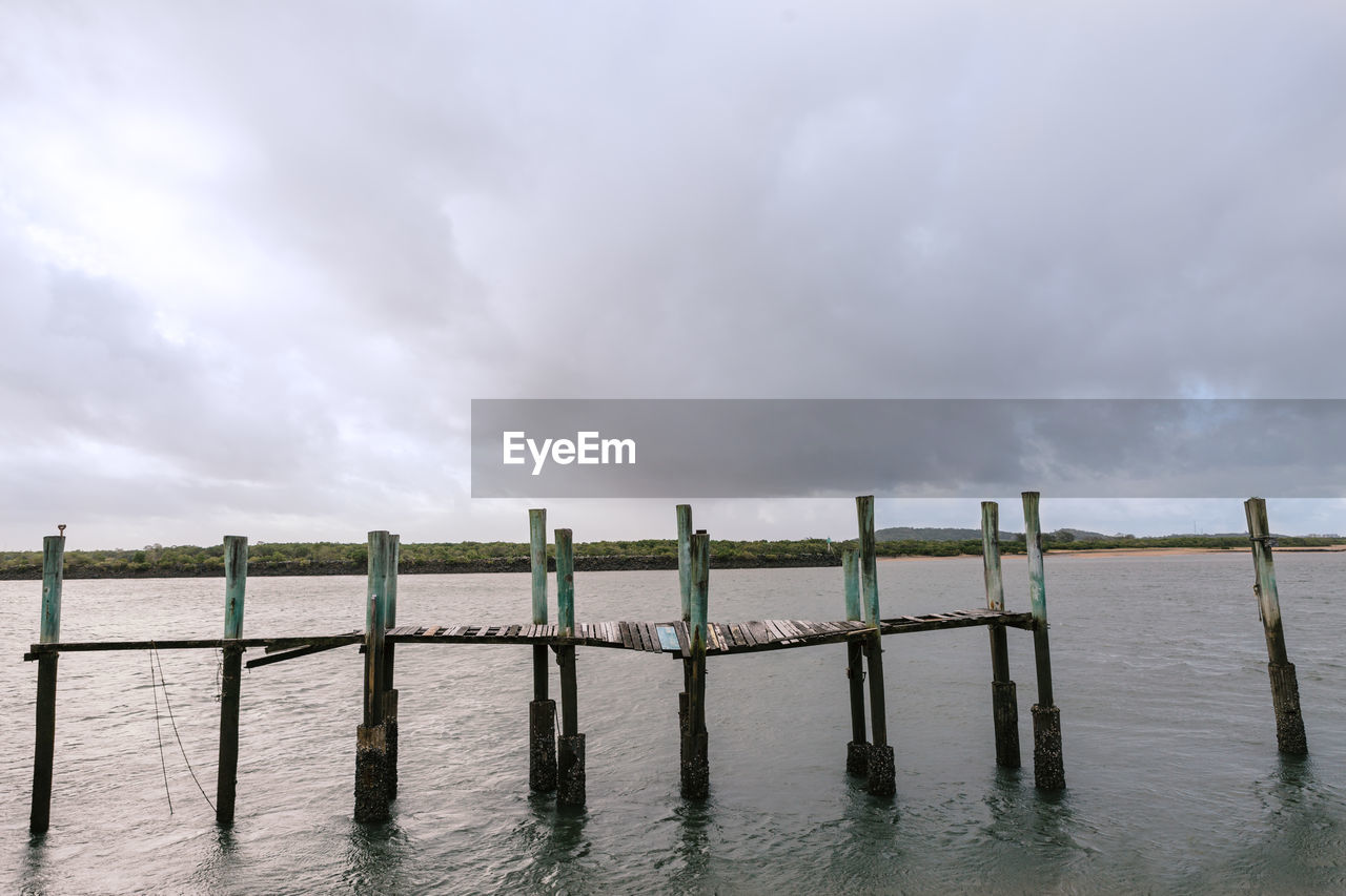 Wooden fence on field against storm clouds