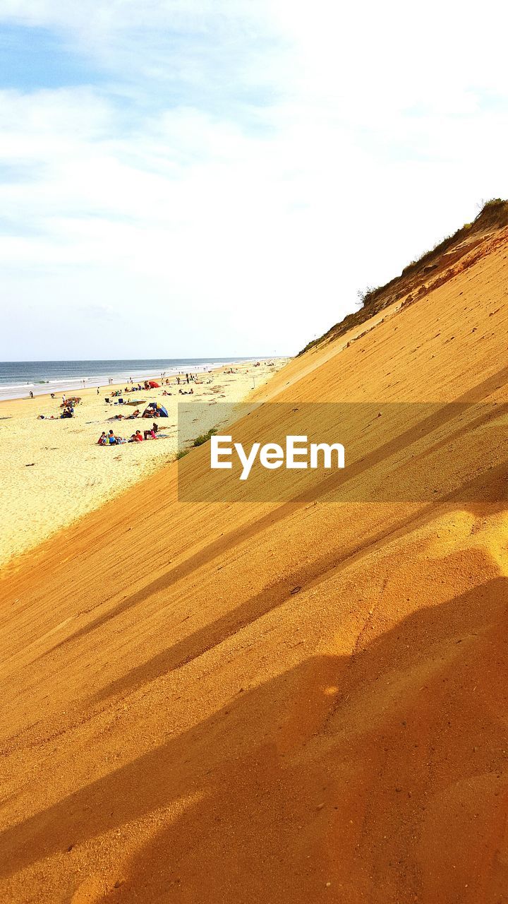 People on sandy beach against sky