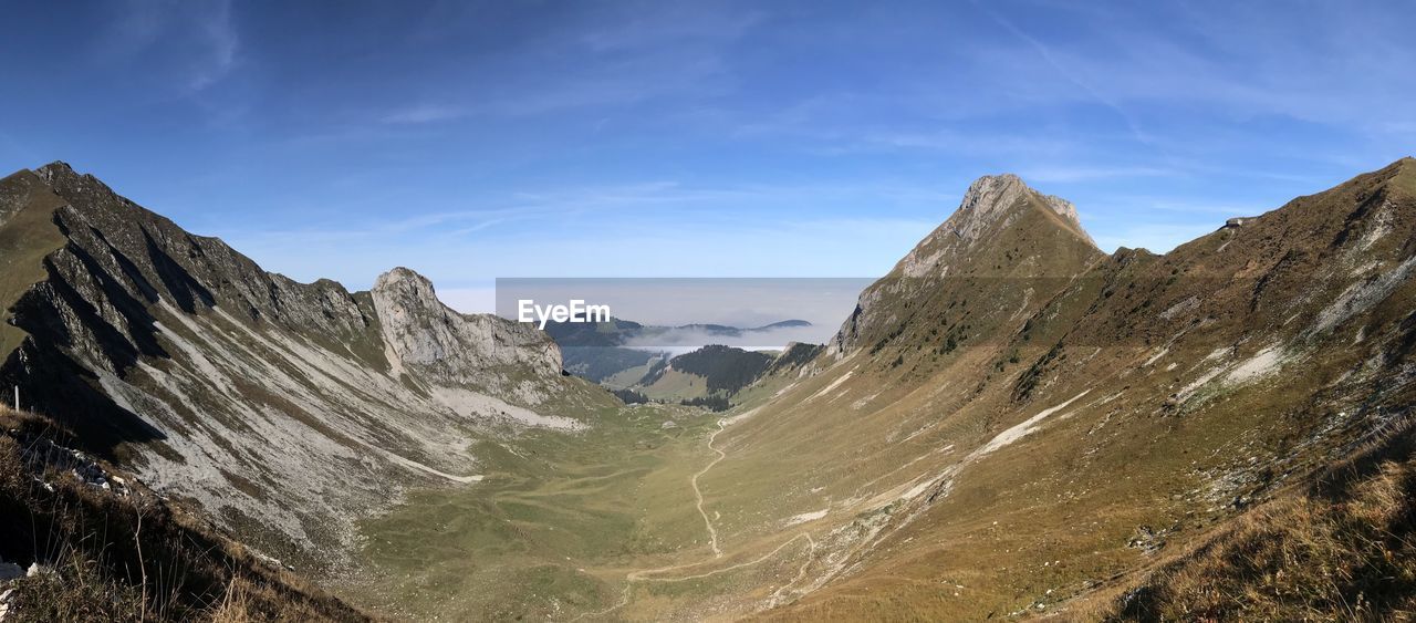 Panoramic view of rocky mountains against blue sky