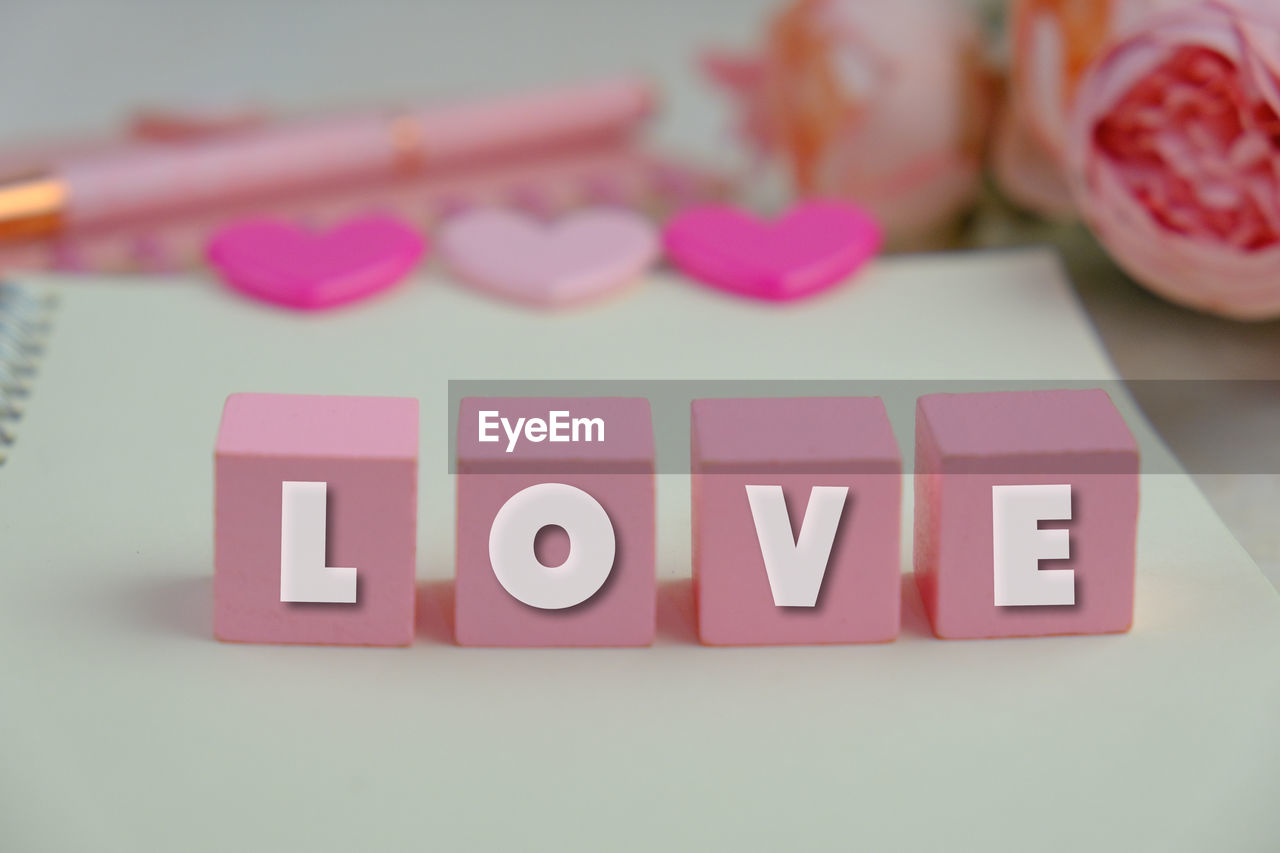 pink, text, indoors, western script, no people, letter, studio shot, still life, close-up, communication, font, toy, education, alphabet, table, paper, party