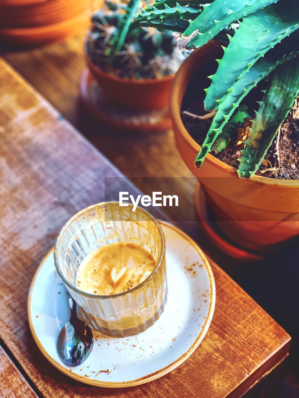 High angle view of coffee on a wooden table with plants, heart shape