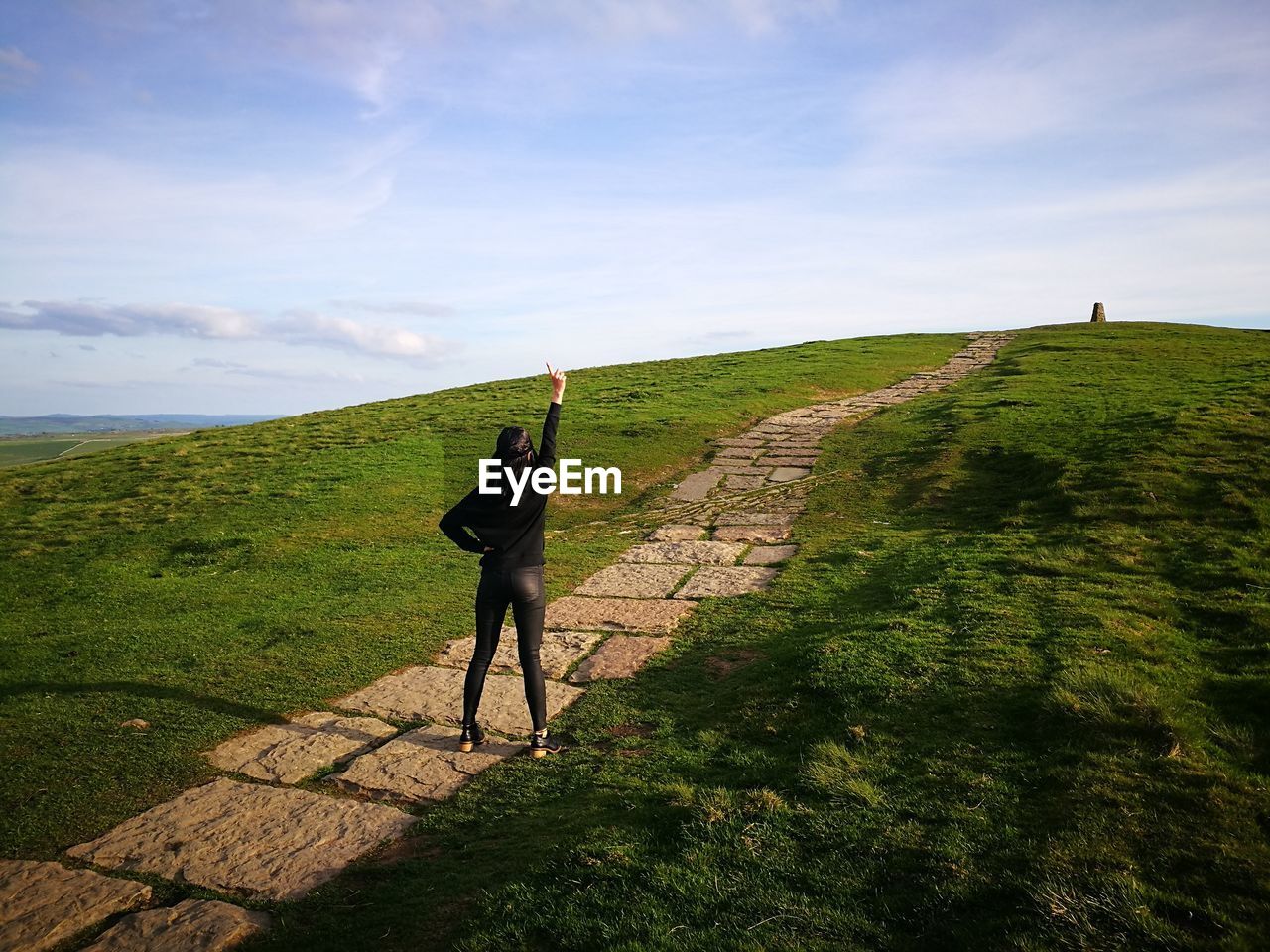 Full length of woman standing on footpath against sky