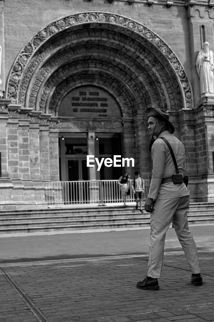 Police officer standing in front of historic building entrance