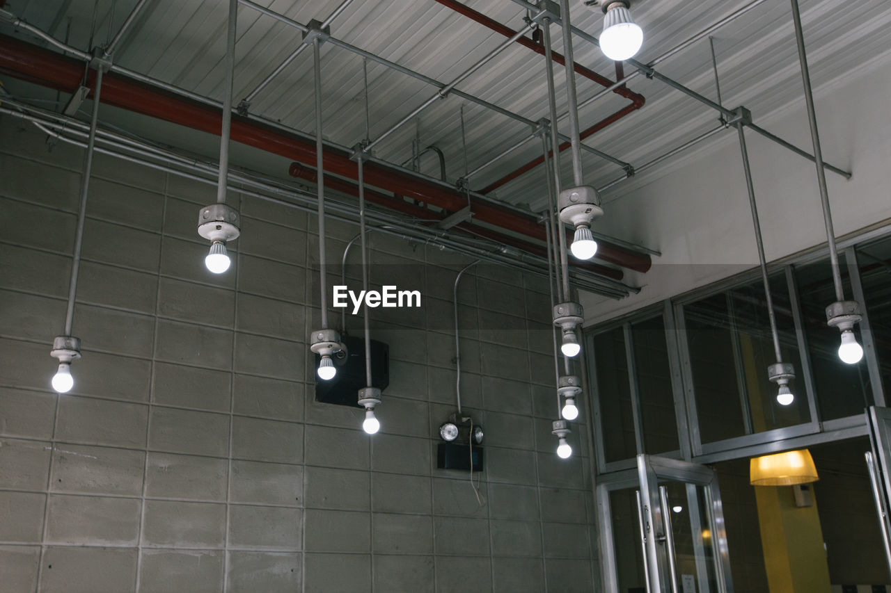 Low angle view of illuminated light bulbs hanging on ceiling