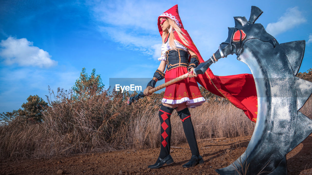 Low angle view of young woman in halloween costume while standing on field against sky