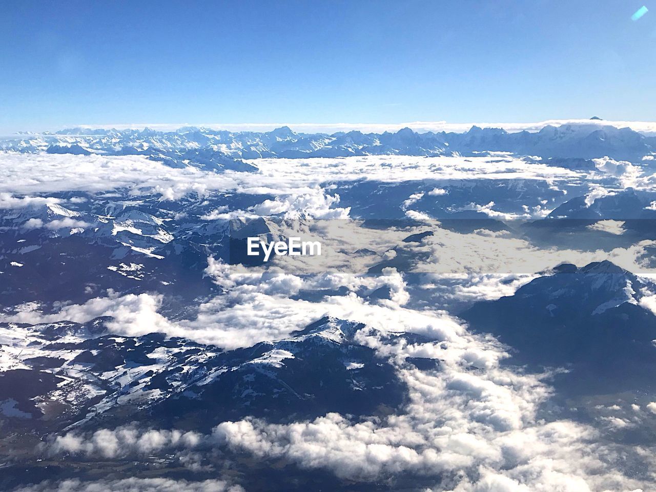 AERIAL VIEW OF SNOWCAPPED LANDSCAPE AGAINST BLUE SKY