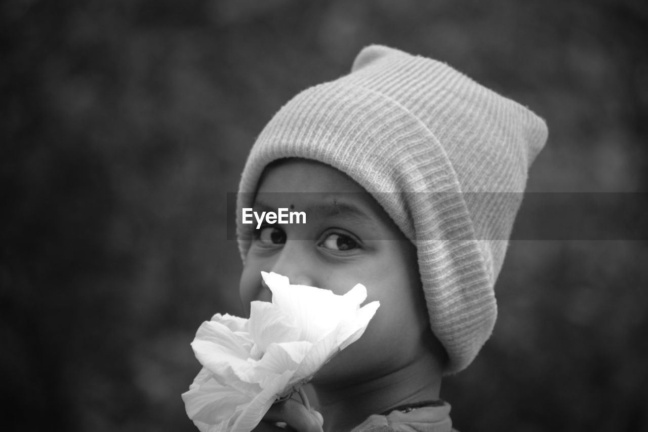 white, childhood, child, one person, portrait, baby, black and white, portrait photography, toddler, hat, headshot, innocence, cute, monochrome photography, close-up, clothing, monochrome, flower, men, nature, black, holding, person, emotion, plant, focus on foreground, looking at camera, outdoors, human face, looking