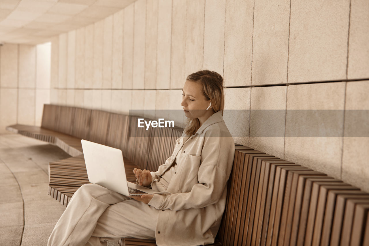 Businesswoman using laptop sitting on bench