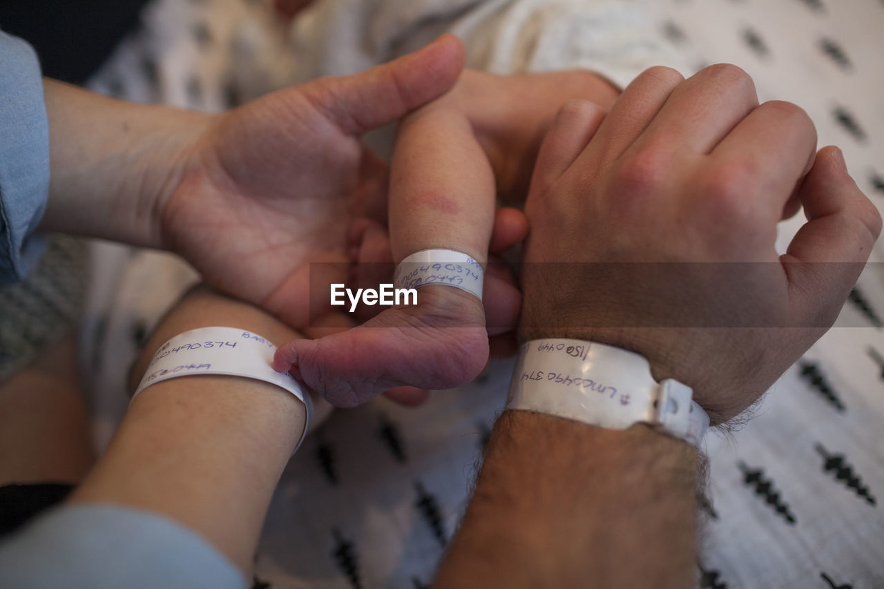 Cropped image of parents and newborn baby with hospital identification bracelets