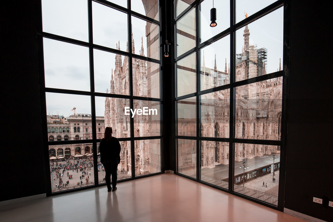 Woman looking through window in city