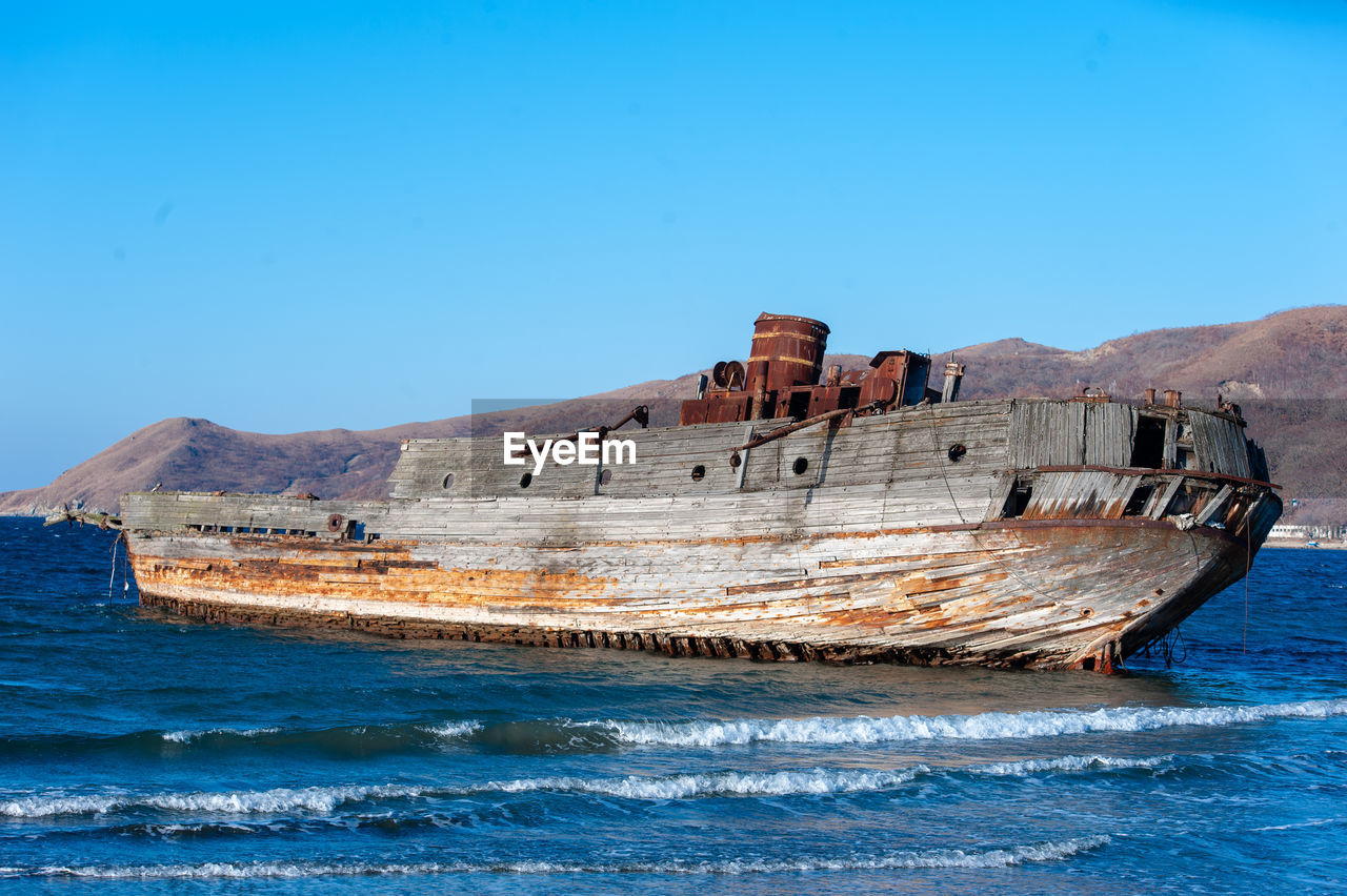 Ship gosth on beach against clear blue sky