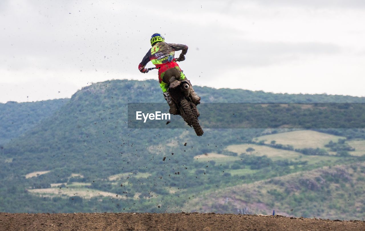 Rear view of biker in mid-air against sky