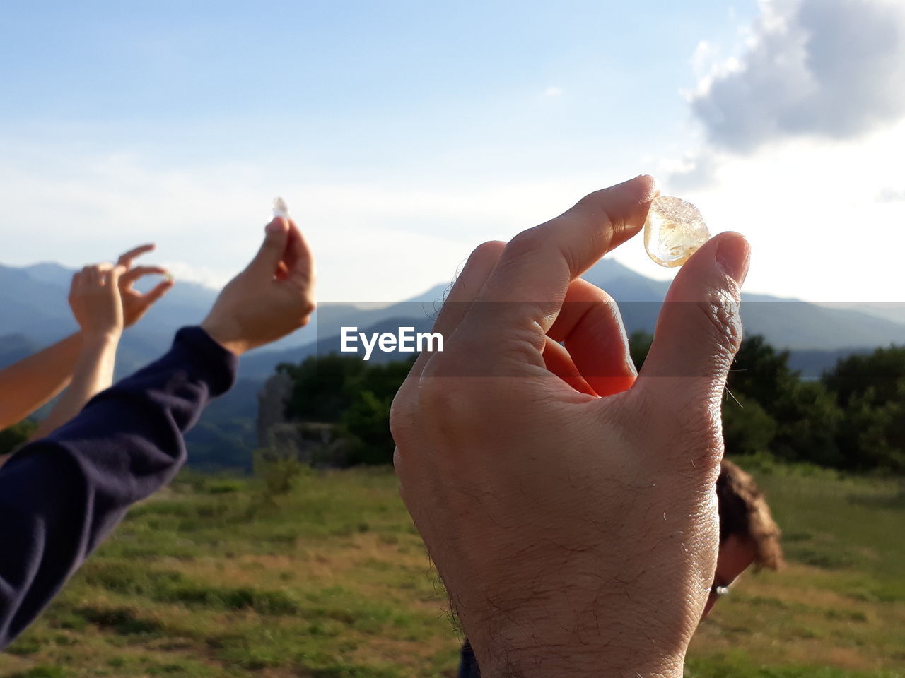 Close-up of people holding ice against sky