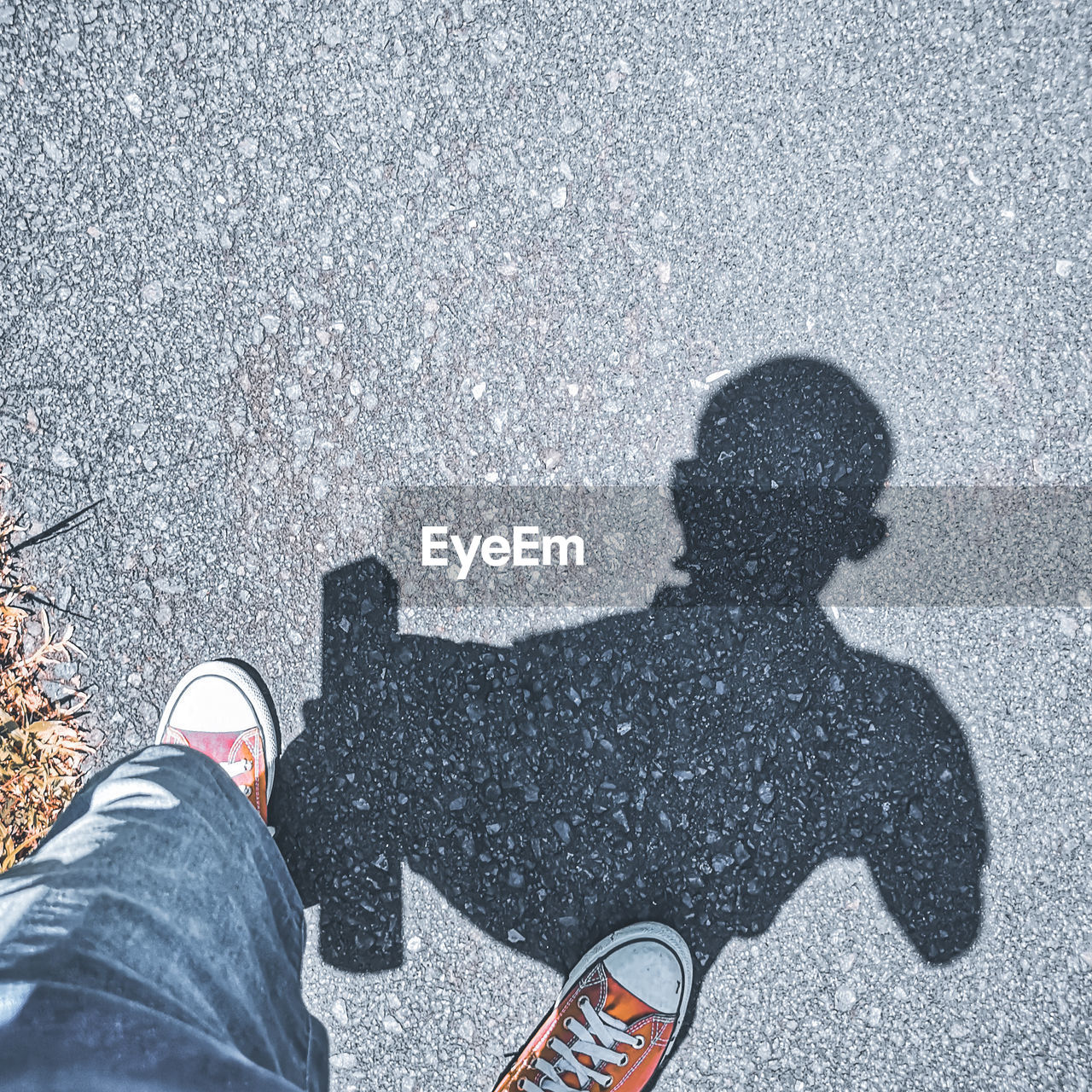 LOW SECTION OF MAN STANDING ON ROAD AGAINST CITY